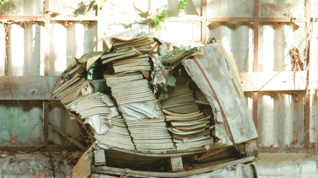 Weathered stack of old binders and files behind a fence